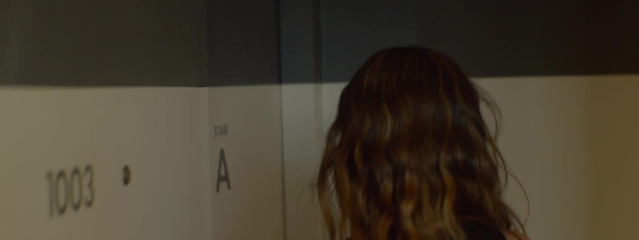 A brown haired woman walks out of her room