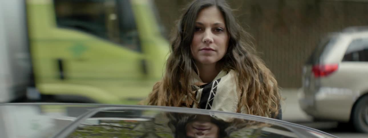A woman stands beside a car on a busy city street