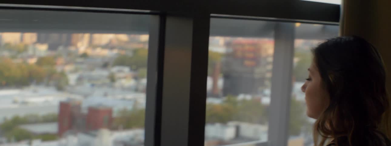 A woman gets out of bed and walks towards the window