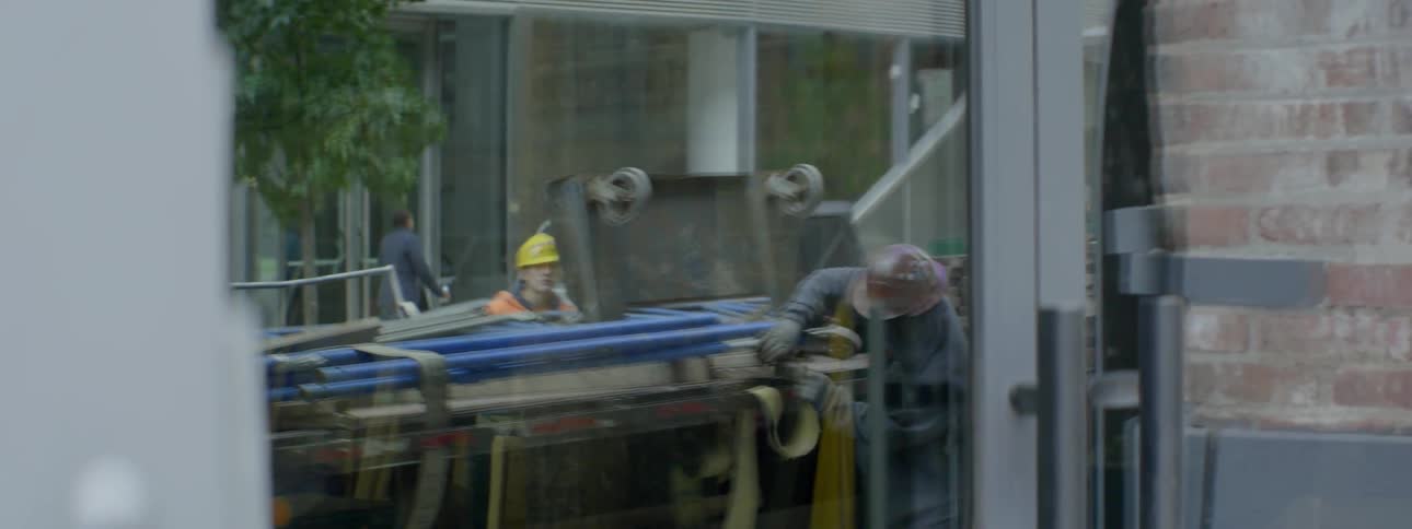 Reflection in glass of people working on a street as a woman walks past