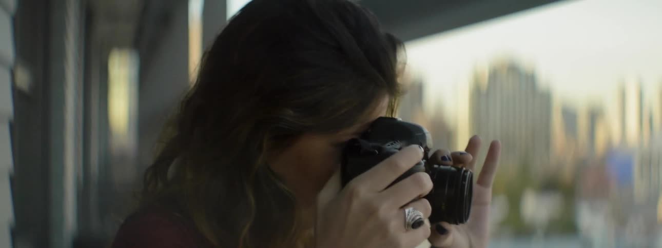 A woman takes photographs of a city below