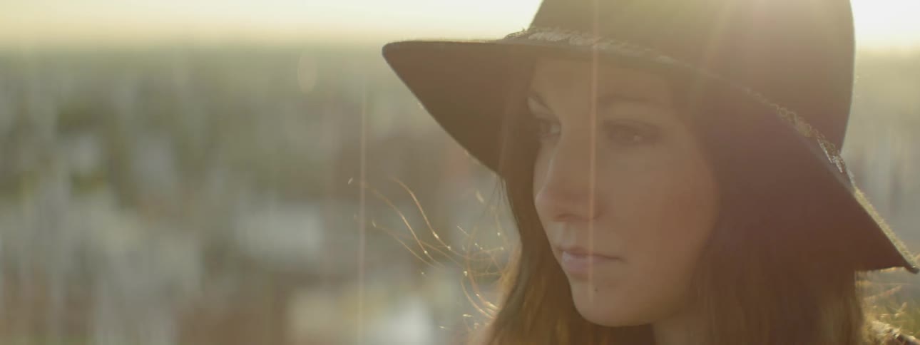 Close up of a woman looking around outside at sunset