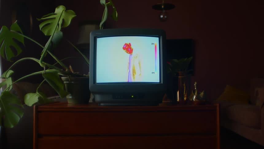 A room with a television set with a couch a wall and a lamp in the background