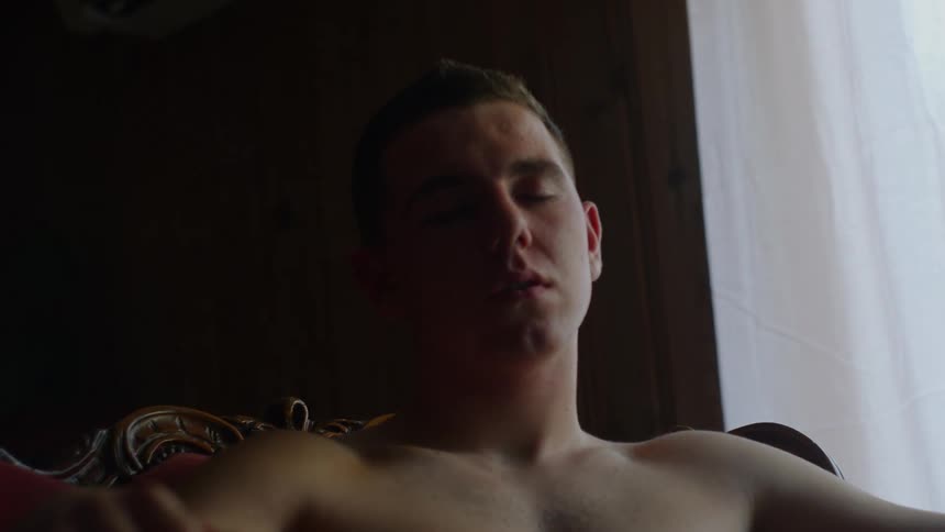 A bare chested man is sitting in a chair sleeping