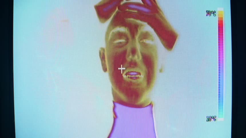 A man under a temperature camera doing weird movements