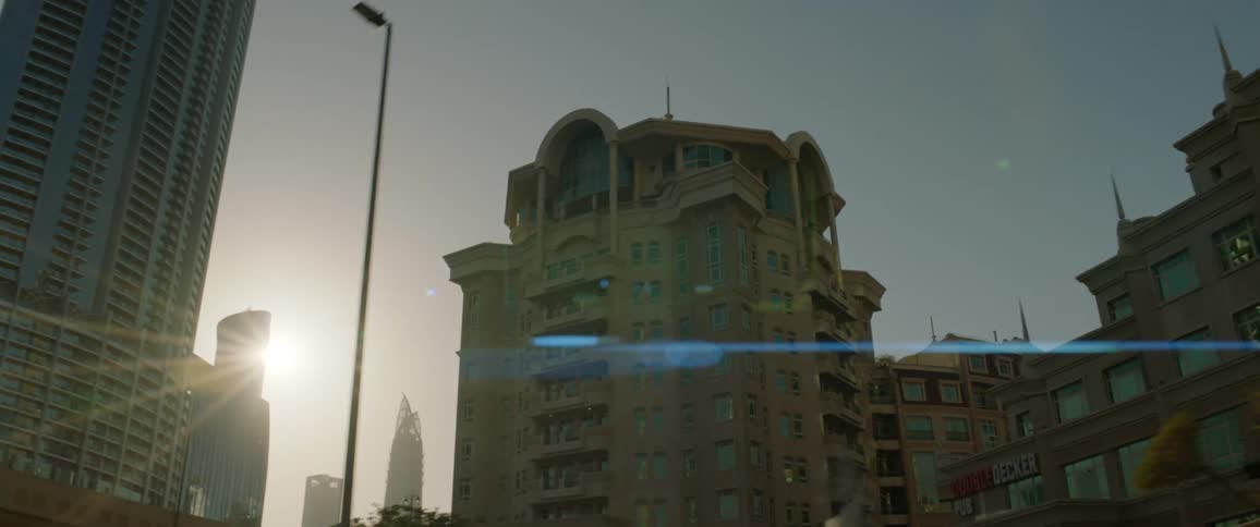Sun shines brightly from clear sky over urban buildings creating glare
