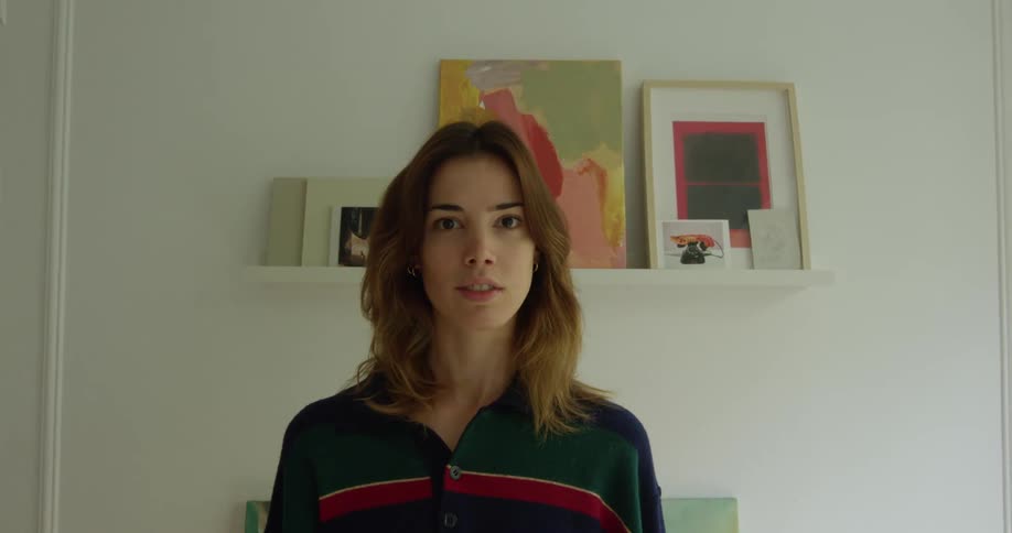 Woman standing on a room in front of pictures looks at the camera