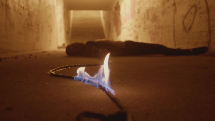 A rope is burning that leads to a man laying on the ground