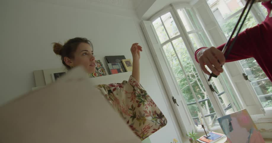 Woman teaching a young man to play violin in the living room of an apartment