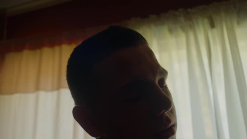 A man in a room with a wall window and curtains in the background