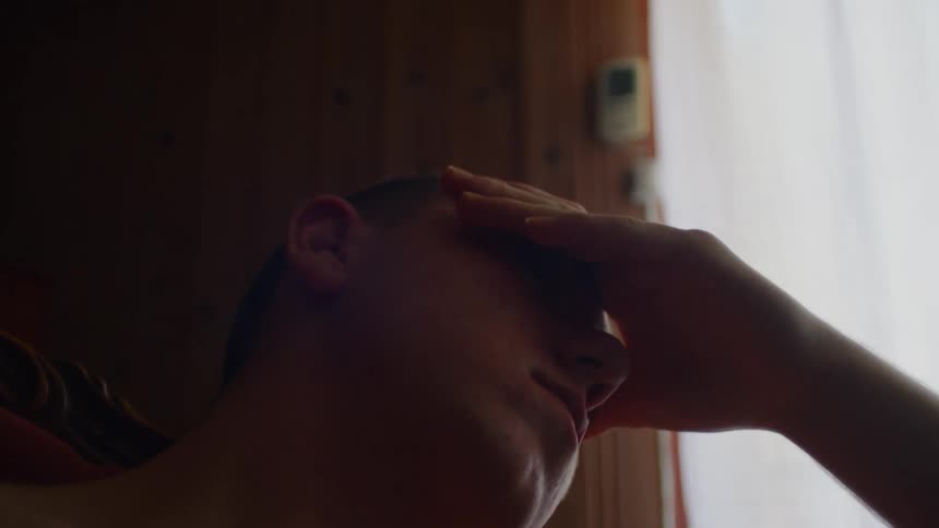 Tired man sits in armchair and rubs his face in room
