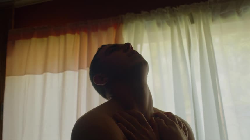 A man is hugging himself and looking at the ceiling