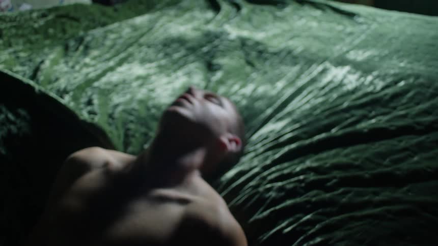Man laying over a green velvet matress having agitates while dreaming
