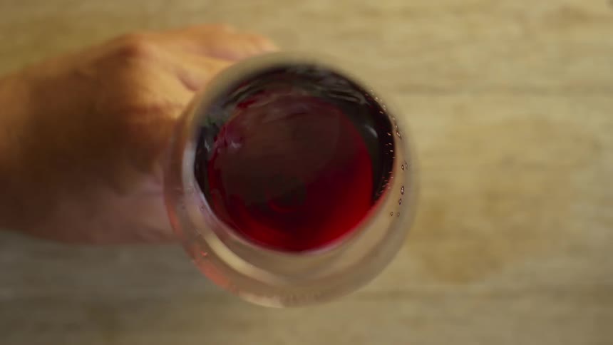 Person holds wine glass and swirls wine letting it catch and reflect light