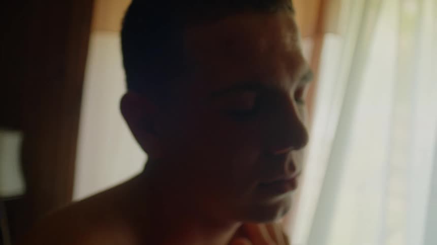 A man in a room with a wall windows and curtains in the background