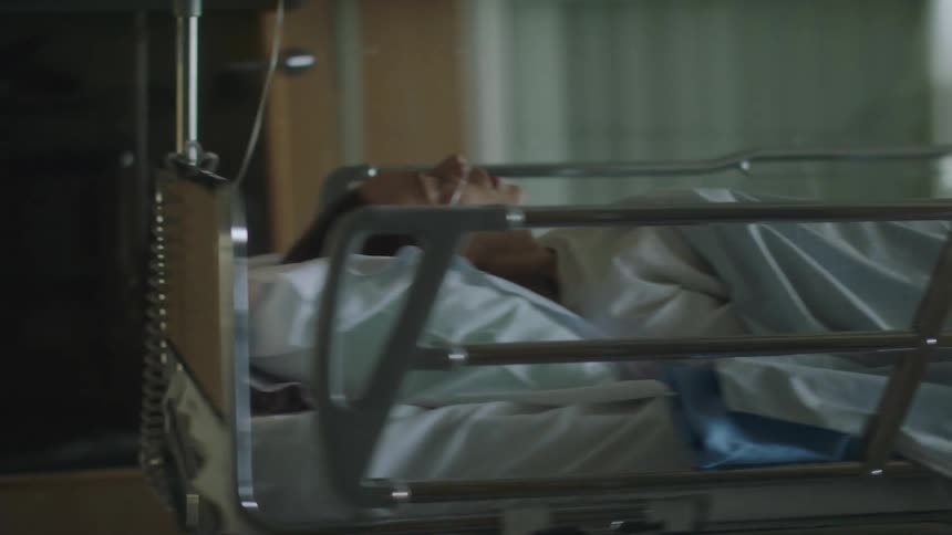 A woman in a hospital being pushed in a hospital bed on wheels