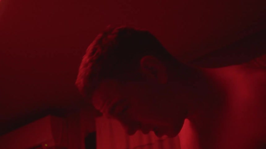 Young shirtless man dancing on a room at home under red strobing lights