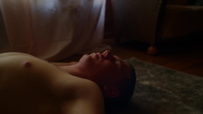 A man laying on the floor on a rug in a room with a window in the background