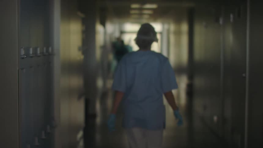 A nurse rushes down a hospital hallway to help a colleague