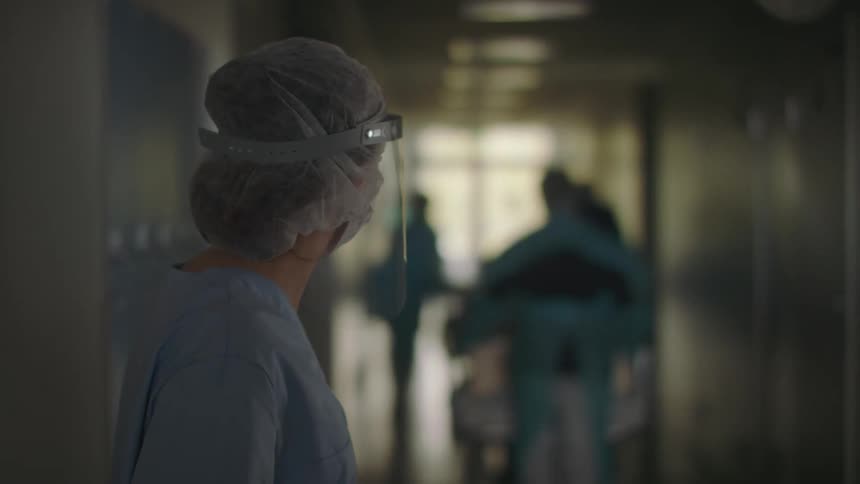 Doctors moving patients laying in beds through a hospital corridor