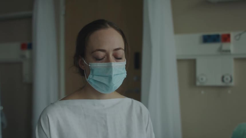 Hospital personnel wearing face shield and mask leans forward to comfort patients next of kin after giving them information