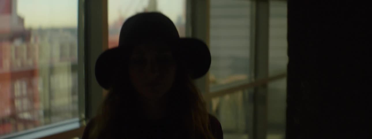 A woman walks past windows into a dark room