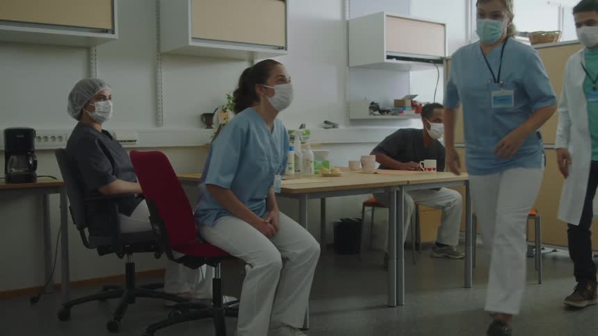 A group of nurses is sitting down while someone talks to them then everyone gets up fast to leave the room