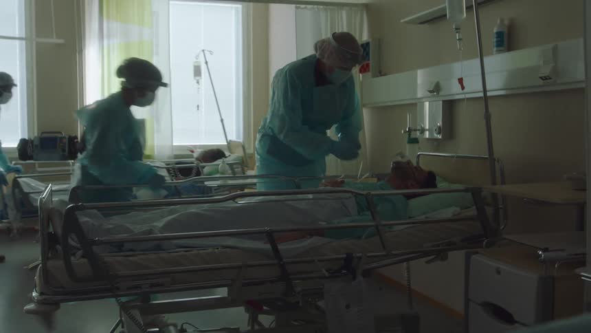 Doctors and nurses pushing beds with patients into hospital rooms