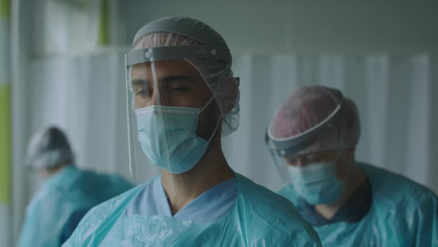 Medical team wearing scrubs and surgical gear including face shields preps