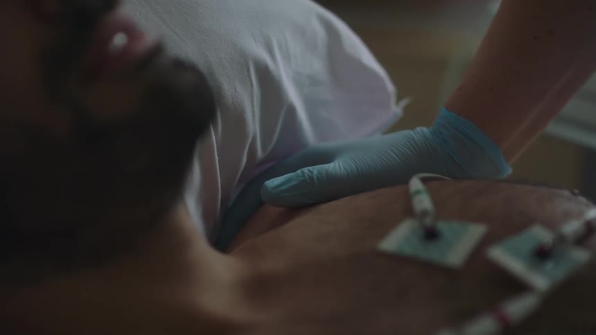 Nurse comforts patient lying in hospital bed with sensors attached to his chest
