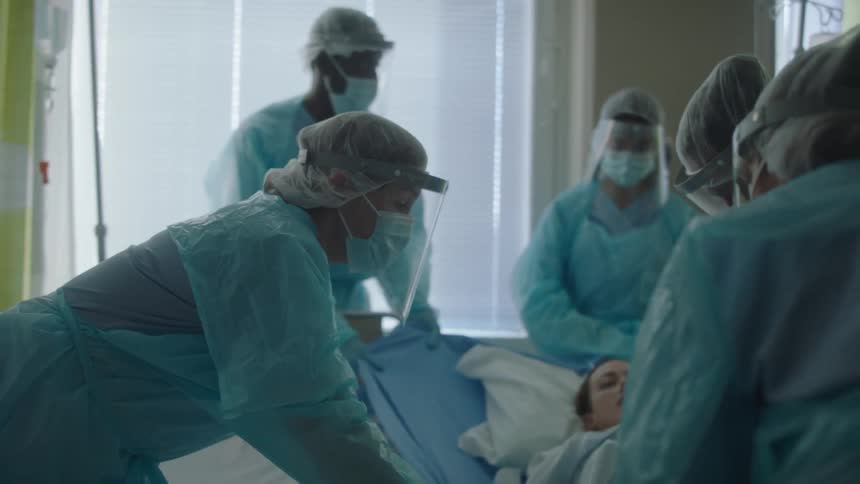 Hospital staff move a woman into a hospital bed