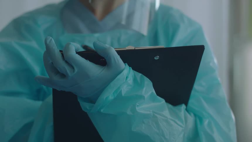 A doctor writing down information on a clipboard