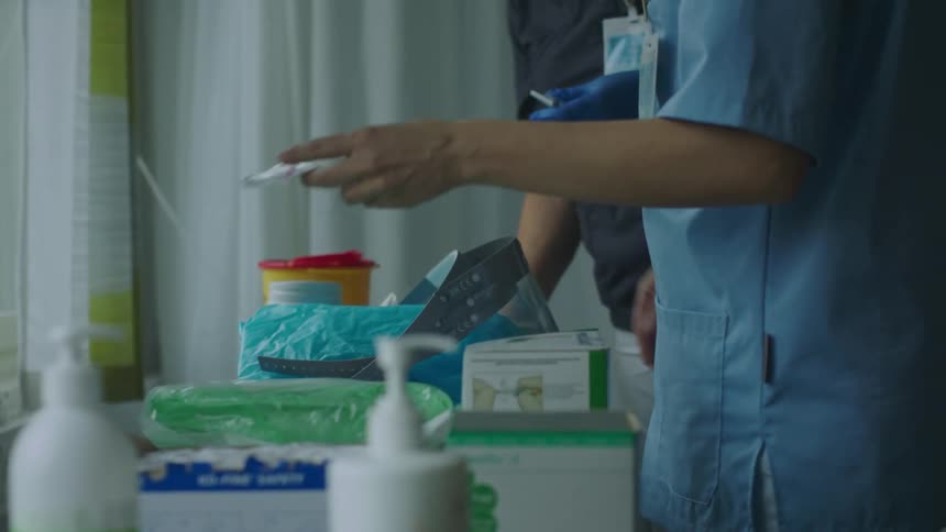 Medical personnel pick up medical supplies standing near window