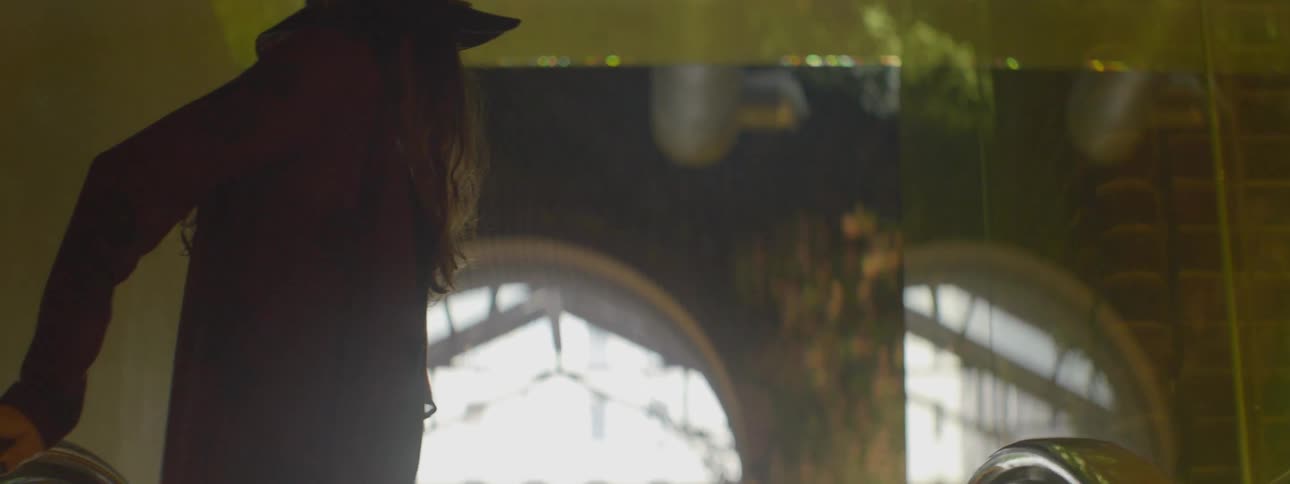 A woman stands in a building and walks out the archway