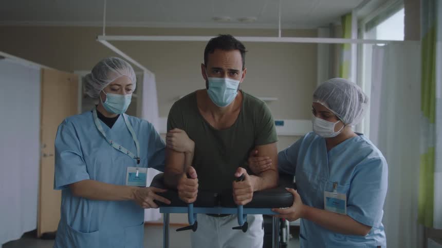 Nurses hold onto a walker as they help a patient walk