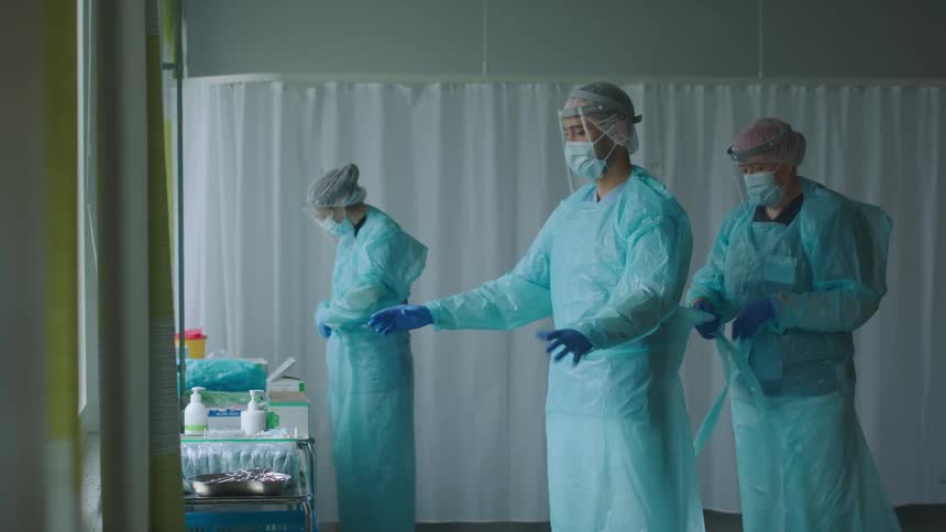 Doctors and nurses wearing protective equipment in a hospital room