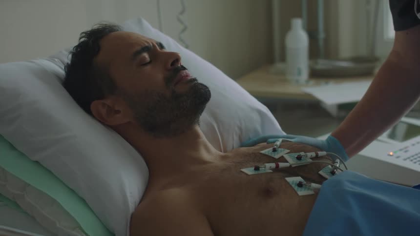 Scared male patient being comforted by a nurse in a hospital room
