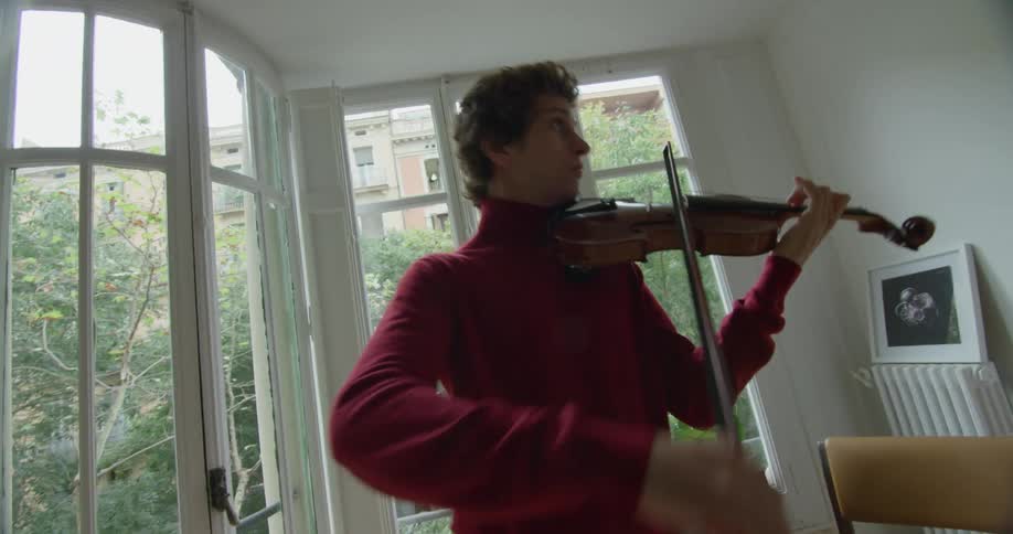 A man is playing the violin in his living room