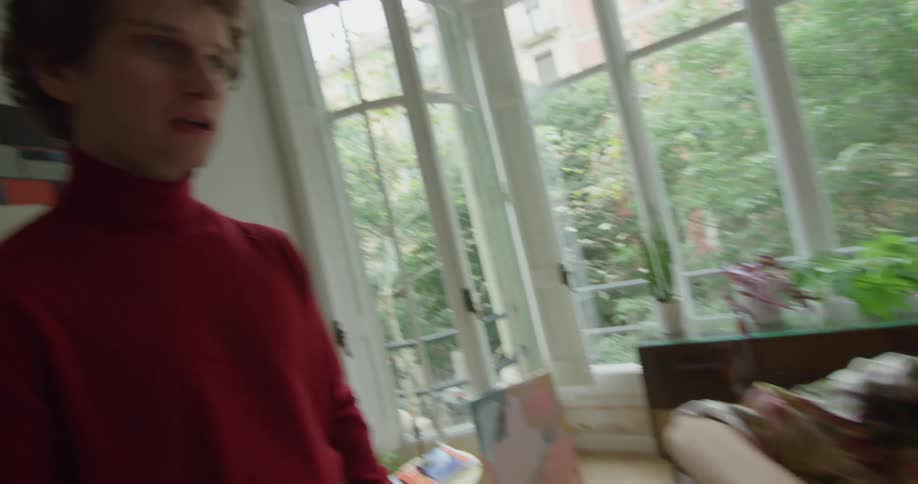 A musician plays a violin in her living room while being coached by an instructor