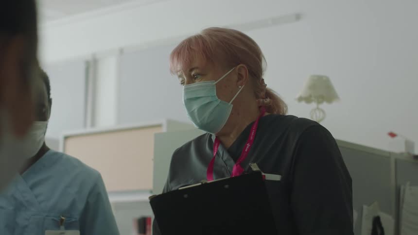 Female healthcare provider wearing a face mask talking to interns