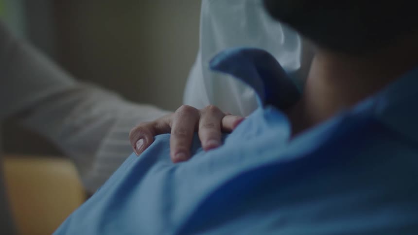A person puts their hand on a mans shoulder