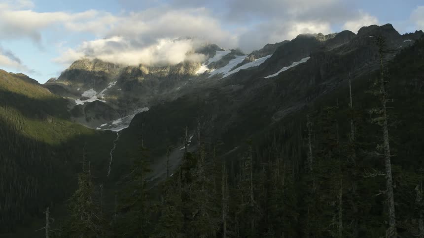 Slow traverse along the tree line of a deep mountain valley