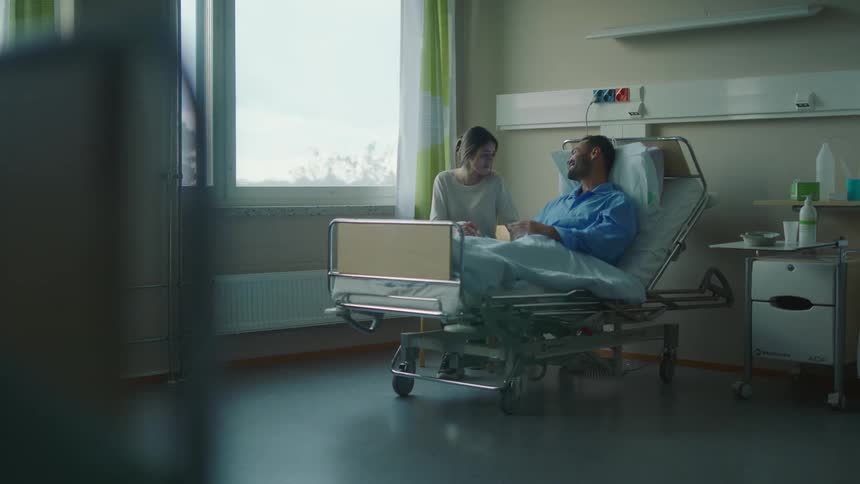 A patient turns his head and smiles at his wife after a doctor delivers good news