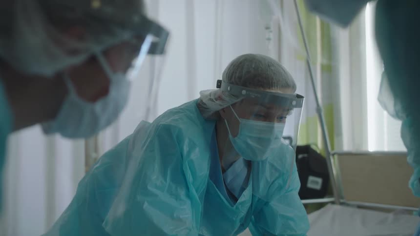 Medical staff lifts a patient onto a gurney in a clinic