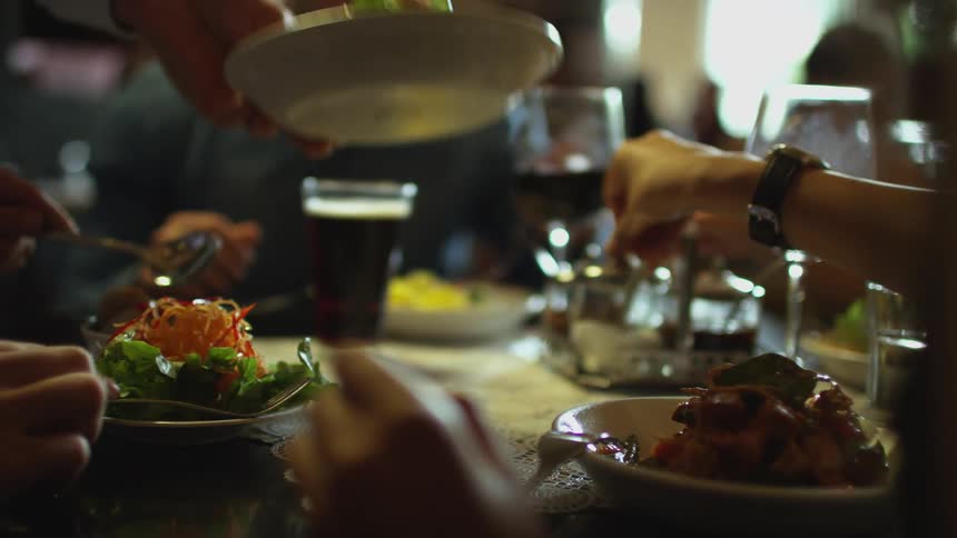 People sitting around a table eating and drinking with food and drinks