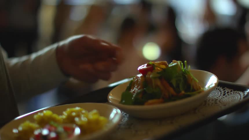 Server serving food to guests inside a restaurant