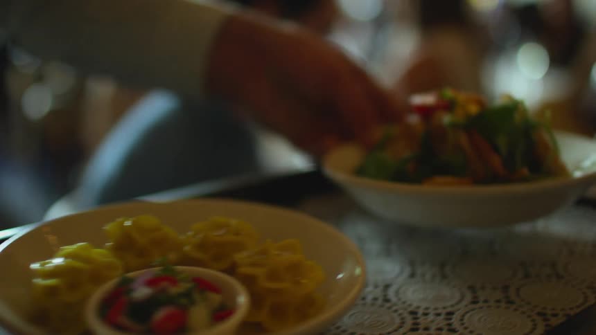 Wait staff serves diners sitting at restaurant table with dishes from tray