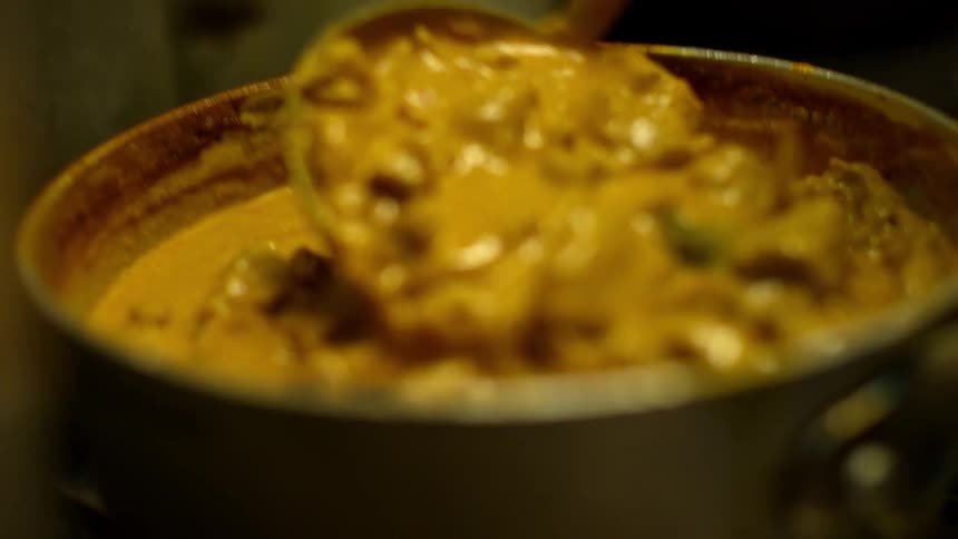 A pot of curry is being stirred