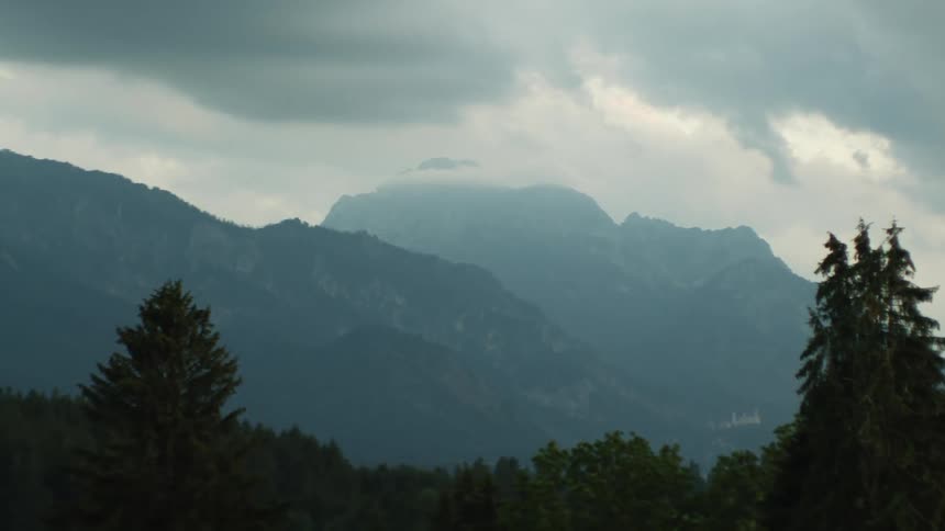 Wide shot of trees and a mountain range on a foggy day