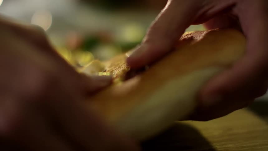 Hands breaking a loaf of bread over a wooden board